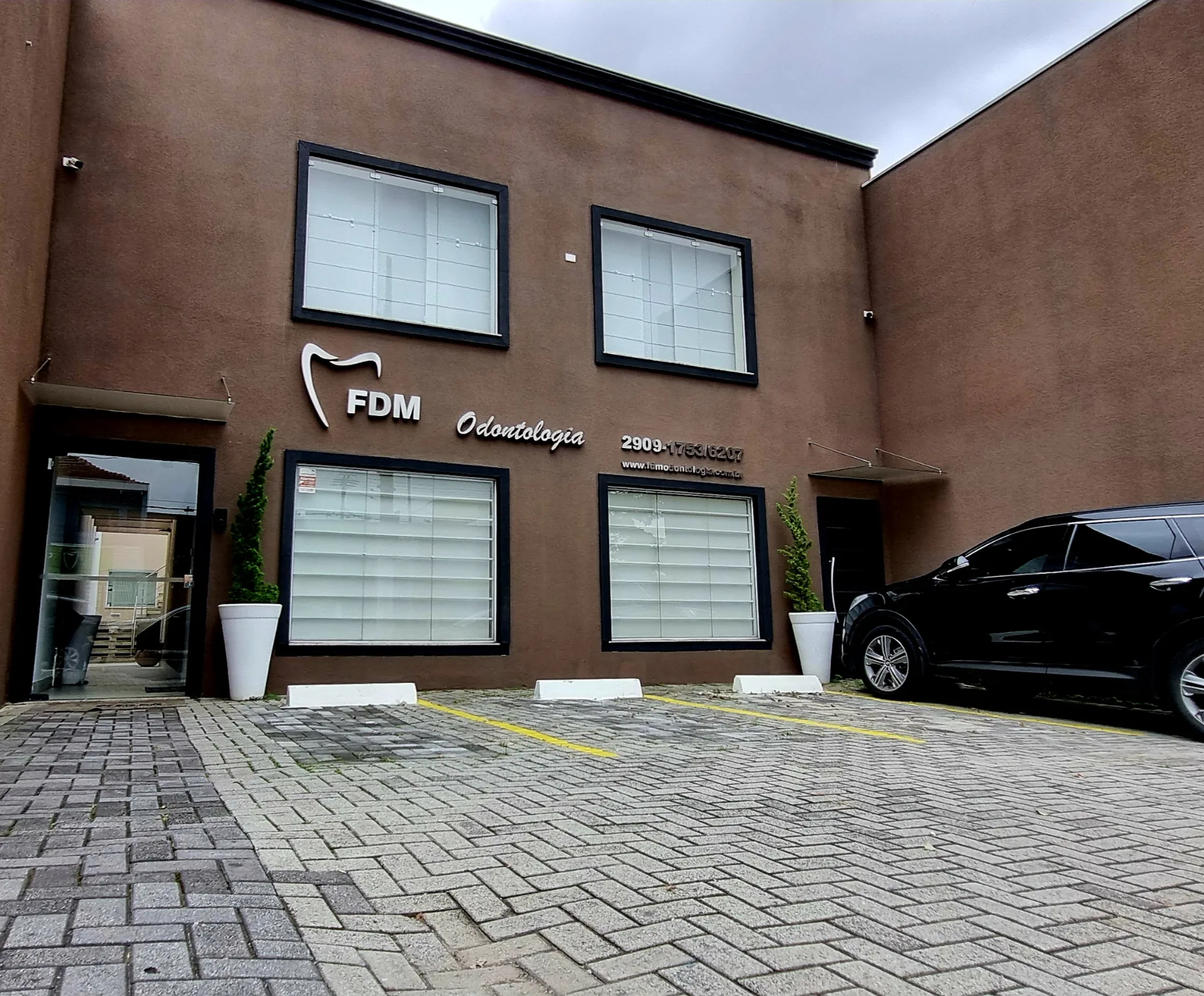 Fachada da FDM Odontologia com entrada e estacionamento