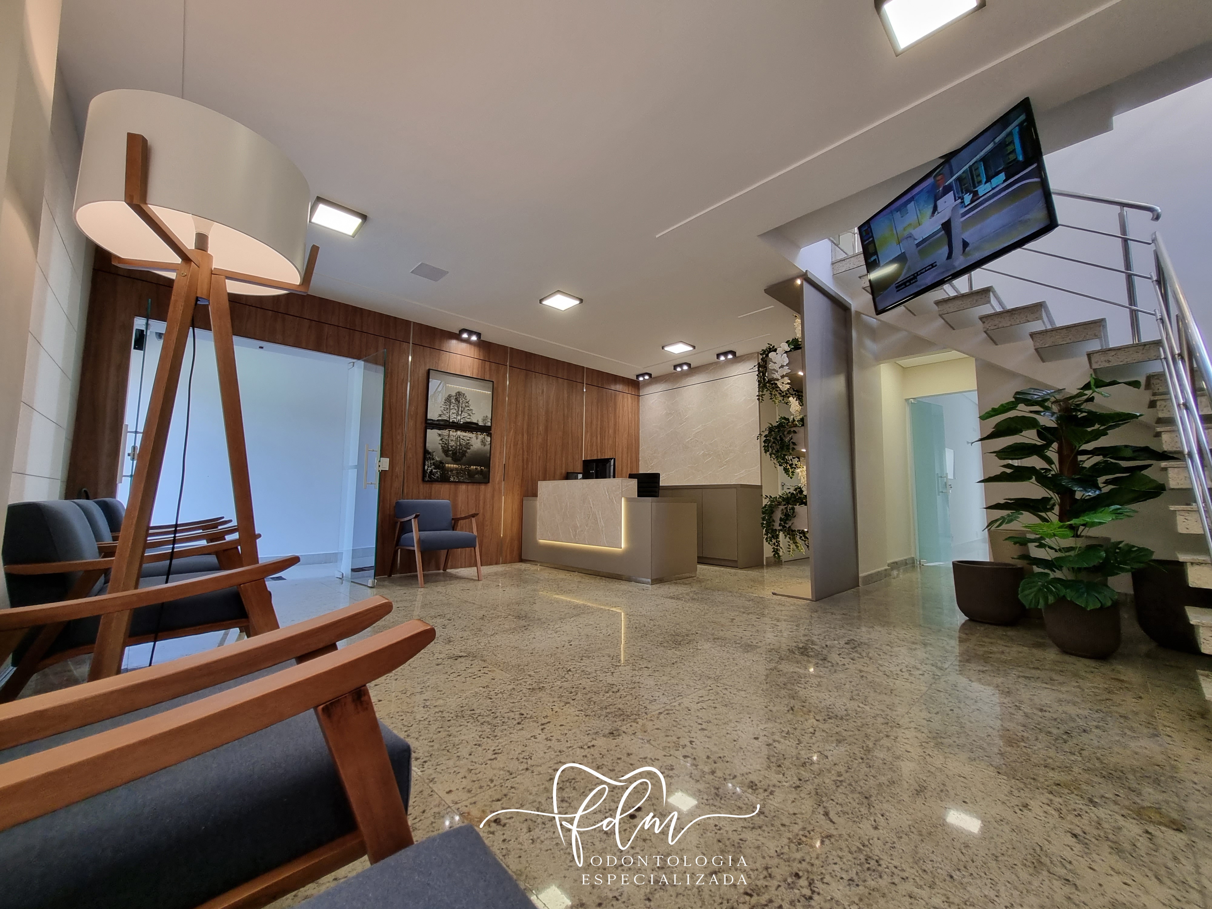 Recepção da clínica com poltronas, balcão e escada